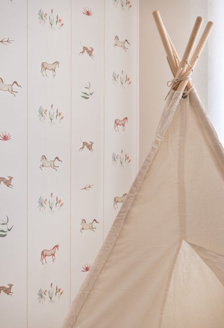 Tienda de campaña beige junto a una pared decorada con ilustraciones de animales.