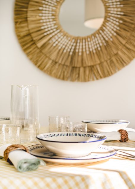 Mesa decorada con platos, cubiertos y un espejo de adorno en el fondo.