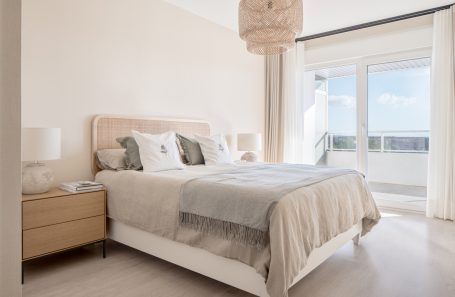 Dormitorio luminoso con cama doble, mesita de noche y balcón. Decoración moderna y suave.