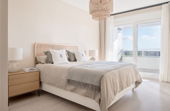 Dormitorio luminoso con cama doble, mesita de noche y ventana al exterior.