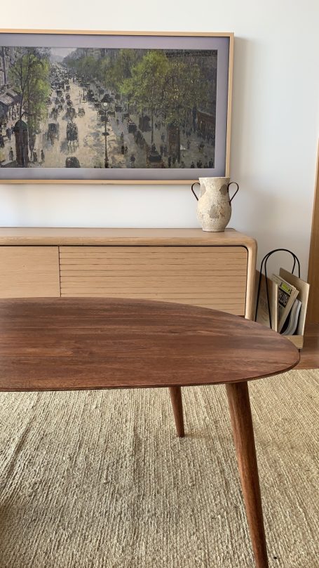Mesa de madera con patas delgadas, fondo de una obra y decoración minimalista.