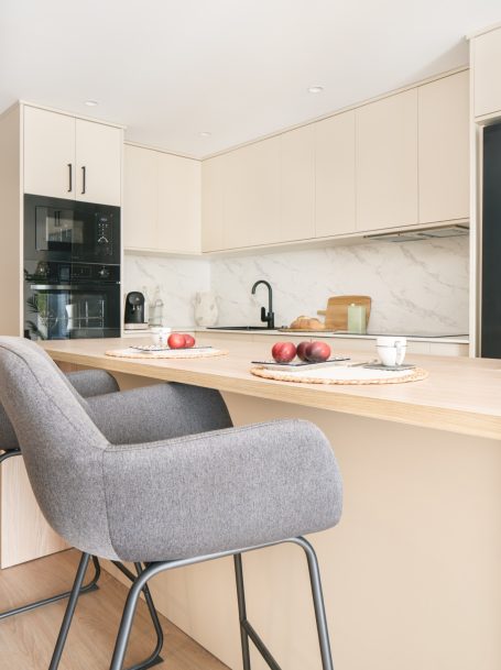 Cocina moderna con mesa, sillas grises y manzanas en la superficie.