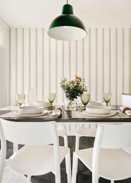 Mesa de comedor con decoraciones minimalistas y flores en un jarrón.