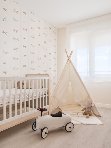 Habitación infantil con cuna, tienda de campaña y un juguete de coche. 