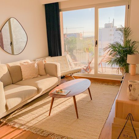 Sala luminosa con sofá, mesa de café y vista exterior. Decoración minimalista.